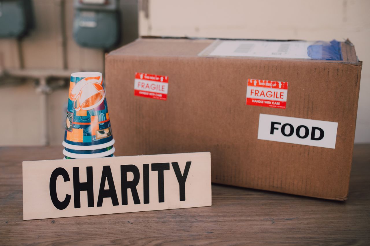 home-hero-bg Image showing a charity donation box packed with food supplies and paper cups.
